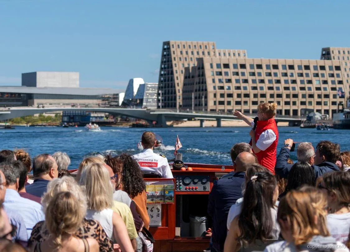 Guide berättar om kanalrundturen i Köpenhamn nära statyn av Den Lilla Sjöjungfrun
